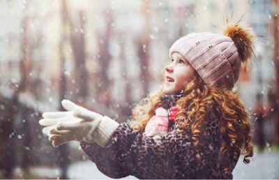 girl with hat in mittens catching snowflakes